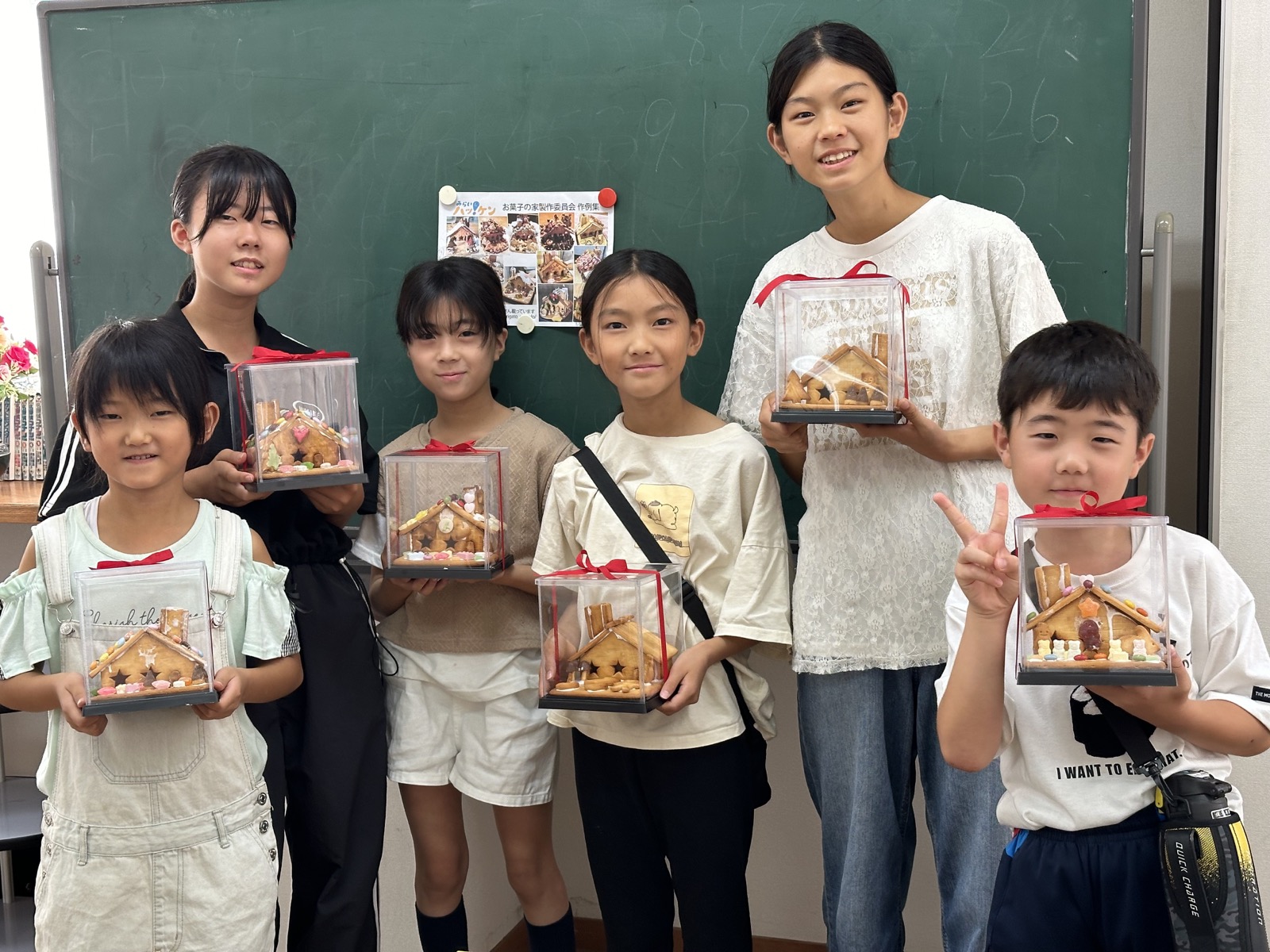 透明ケースに入れたお菓子の家を持つ教室の参加者